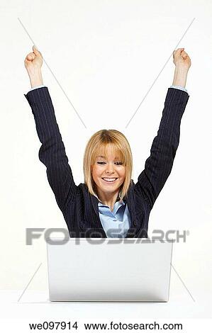 Happy blonde business woman working in office with laptop raising hands for victory View Large Photo Image Picture - Happy blonde business woman working in office with laptop raising hands for victory. Fotosearch