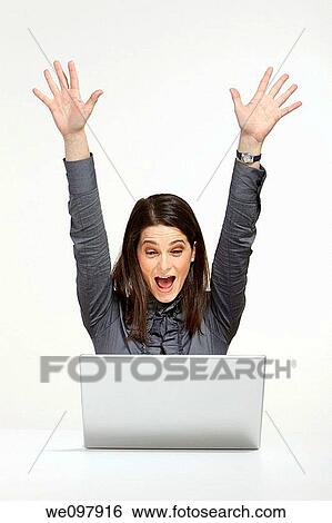 Happy brunette business woman working on her laptop rising hands as victory View Large Photo Image Stock Photograph - Happy brunette business woman working on her laptop rising hands as victory. Fotosearch