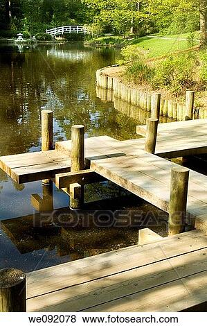 Stock Photo - japanese zen garden boardwalk over koi pond arched moon bridge in background. Fotosearch