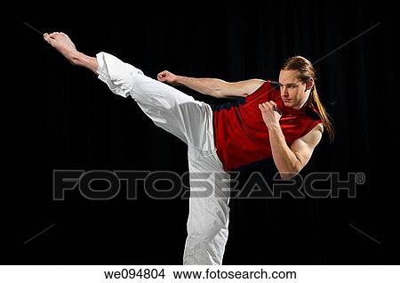 Male Karate fighter throwing a side kick in front of a black curtain View Large Photo Image Picture - Male Karate fighter throwing a side kick in front of a black curtain. Fotosearch