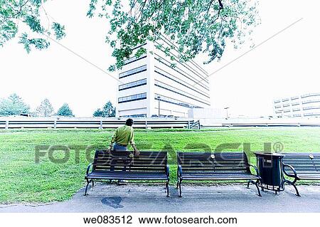 Man standing by wooden benches in a city park. View Large Photo Image Stock Image - Man standing by wooden benches in a city park.. Fotosearch
