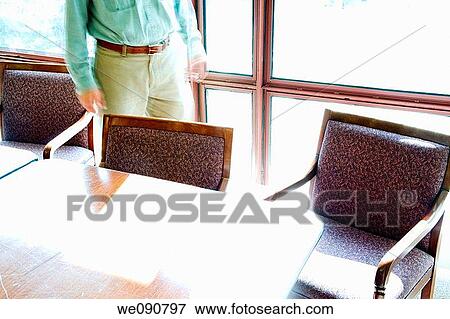 Man walking behind an office table and chairs View Large Photo Image Stock Photo - Man walking behind an office table and chairs. Fotosearch