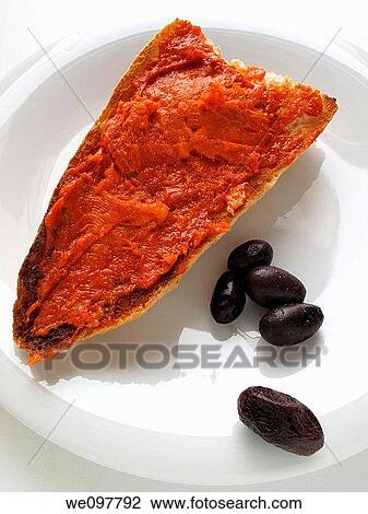 Stock Image - Mayorquina sobrasada toast and black olives. Fotosearch