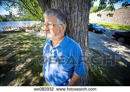Middle-age man, with glasses and a beard, standing by a tree. View Large Photo Image Stock Image - Middle-age man, with glasses and a beard, standing by a tree.. Fotosearch