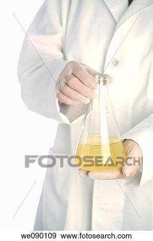 Person in lab coat holds beaker of liquid View Large Photo Image Stock Photo - Person in lab coat holds beaker of liquid. Fotosearch