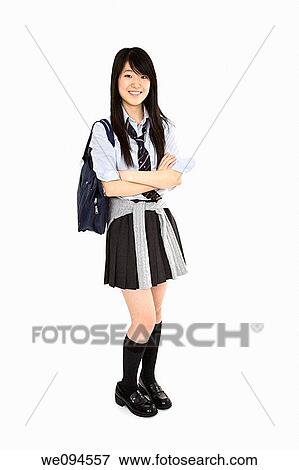 Stock Photo - Portrait of a female Asian teenager dressed in the traditional Japanese schoolgirl clothing Uniforms are worn by most of the female school children in Japan She is standing on a white background and smiling. Fotosearch