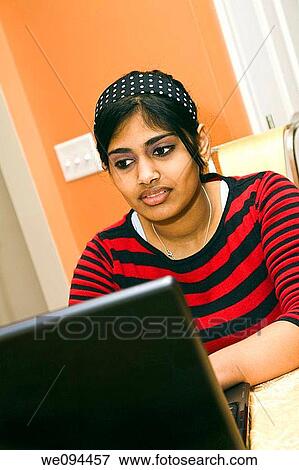 Stock Photo - Portrait of Indian teenager working with a laptop conputer. Fotosearch