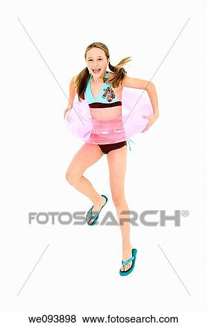 Preteen caucasian girl jumping on a white background in a swimsuit holdong a beach toy and smiling View Large Photo Image Stock Photo - Preteen caucasian girl jumping on a white background in a swimsuit holdong a beach toy and smiling. Fotosearch