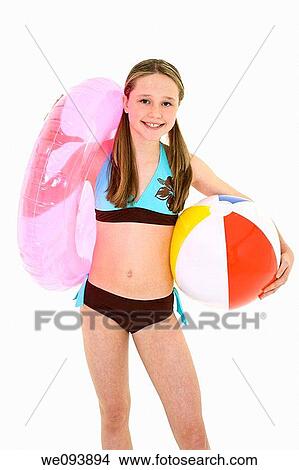 Preteen caucasian girl standing on a white background in a swimsuit holding beach toys and smiling View Large Photo Image Picture - Preteen caucasian girl standing on a white background in a swimsuit holding beach toys and smiling. Fotosearch