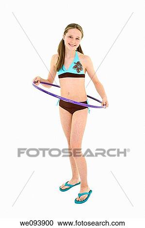 Stock Image - Preteen caucasian girl standing on a white background in a swimsuit holding a hula hoop. Fotosearch