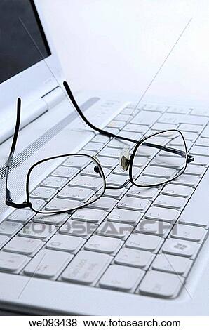 Reading glasses resting on the white keyboard of an open laptop computer View Large Photo Image Stock Photo - Reading glasses resting on the white keyboard of an open laptop computer. Fotosearch