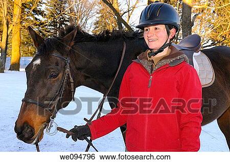 Stock Photograph - Relaxed happy teenage rider walking her horse back to the barn after a winter hack. Fotosearch