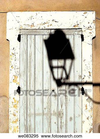 Stock Photography - Shadow of an ornate lamp cast on an old door, Avignon, France. Fotosearch