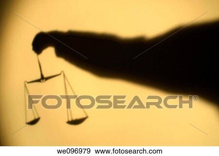 Stock Photo - Shadow of the scales of Justice brandished by a man arm. Fotosearch