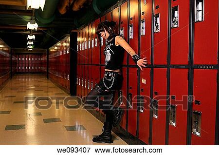 Stock Photo - Sinister looking young female heavy metal punk rocker leaning on school lockers in a basement. Fotosearch