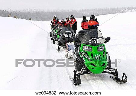 Stock Image - Snowmobiler group stopped for pictures on Norris Canyon Road in Yellowstone National Park in winter. Fotosearch