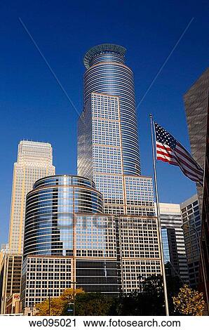 Stock Image - South Sixth and Wells Fargo highrise Towers with blue sky and American flag in downtown Minneapolis. Fotosearch