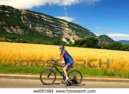 Picture - Sporty woman on a bike tour in a mountainous landscape. Fotosearch