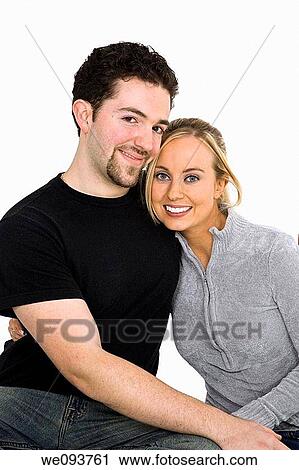 Studio photograph of young Caucasian couple posing with their arms around each other on a white background View Large Photo Image Stock Image - Studio photograph of young Caucasian couple posing with their arms around each other on a white background. Fotosearch