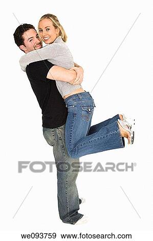 Stock Photo - Studio photograph of young Caucasian couple posing with their arms around each other on a white background. Fotosearch