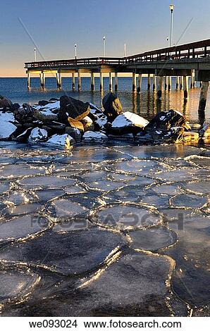 Sunset at Toronto Center Island Pier in winter with ice flows and pylon reflections View Large Photo Image Picture - Sunset at Toronto Center Island Pier in winter with ice flows and pylon reflections. Fotosearch