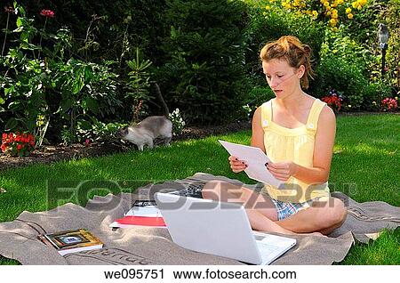 Teenager doing homework with laptop on a blanket in the back yard shade with running cat View Large Photo Image Stock Image - Teenager doing homework with laptop on a blanket in the back yard shade with running cat. Fotosearch