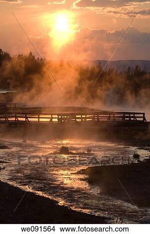 The setting sun reflecting on Firehole Lake geothermal area and boardwalk suggests a boiling pool of magma below View Large Photo Image Picture - The setting sun reflecting on Firehole Lake geothermal area and boardwalk suggests a boiling pool of magma below. Fotosearch