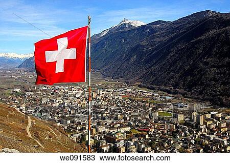 The Swiss flag flutters above the town of Martigny in the Rhone valley, right peak Pierre Avoi, Martigny, Valais, Switzerland View Large Photo Image Stock Image - The Swiss flag flutters above the town of Martigny in the Rhone valley, right peak Pierre Avoi, Martigny, Valais, Switzerland. Fotosearch