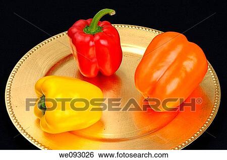 Three bell peppers yellow orange red on a gold plate on black cloth View Large Photo Image Stock Photograph - Three bell peppers yellow orange red on a gold plate on black cloth. Fotosearch