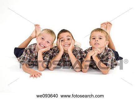 Stock Image - Three Caucasian boys laying on a white background and smiling. Fotosearch