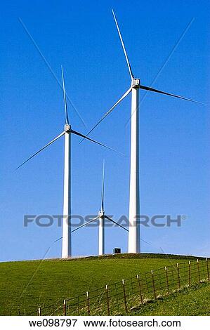 Stock Photo - Three windmills in a grassy field with a fence against a deep blue sky Livermore, California. Fotosearch
