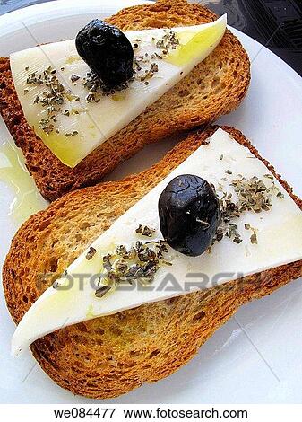 Stock Photo - Toasts with cured cheese, oil and black olives. Fotosearch