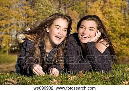 Two caucasian female teens laying on grass posing for a picture View Large Photo Image Stock Image - Two caucasian female teens laying on grass posing for a picture. Fotosearch
