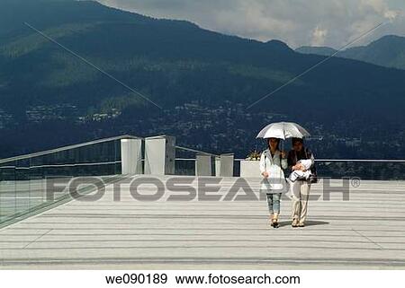 two women walk with umbrella at the Vancouver Convention Centre, Vancouver, BC, Canada View Large Photo Image Stock Photo - two women walk with umbrella at the Vancouver Convention Centre, Vancouver, BC, Canada. Fotosearch