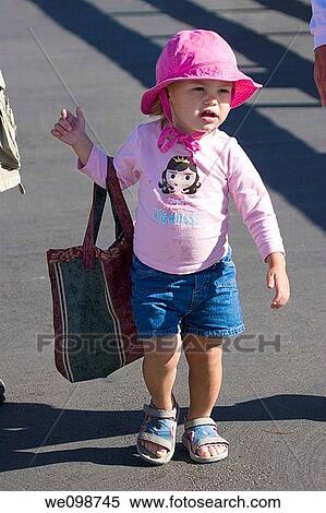 Two year old girl in a pink outfit walking along while holding a bag that is too big for her She seems to be playing grownup in carrying her mother's bag View Large Photo Image Stock Photography - Two year old girl in a pink outfit walking along while holding a bag that is too big for her She seems to be playing grownup in carrying her mother's bag. Fotosearch