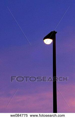 View of a silhouetted lit lamppost against a purple and blue cloudy sky at sunrise View Large Photo Image Stock Photography - View of a silhouetted lit lamppost against a purple and blue cloudy sky at sunrise. Fotosearch