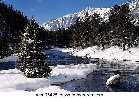 Stock Photography - Wading fishermen on Madison River in winter with snowy Rocky mountain Madison Range Montana. Fotosearch