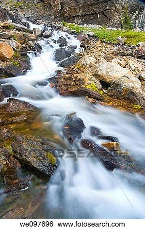 waterfall in rocky mountains, water flowing over rocks View Large Photo Image Stock Photograph - waterfall in rocky mountains, water flowing over rocks. Fotosearch