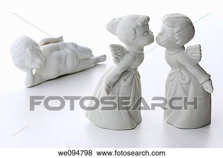 White porcelain boy and girl angels kissing with a third angel watching in the background View Large Photo Image Stock Photo - White porcelain boy and girl angels kissing with a third angel watching in the background. Fotosearch