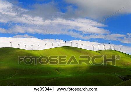 Stock Image - Winter sun on the rolling green hills of the Altamont Pass wind farm in California. Fotosearch