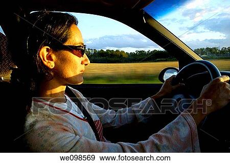 Woman driving a car at sunset View Large Photo Image Stock Photo - Woman driving a car at sunset. Fotosearch