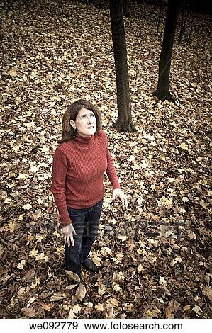 Woman standing on fallen leaves in her back yard View Large Photo Image Stock Photo - Woman standing on fallen leaves in her back yard. Fotosearch