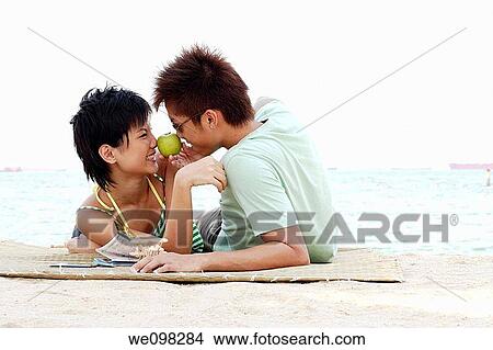 Young asian couple facing each other with green apple View Large Photo Image Picture - Young asian couple facing each other with green apple. Fotosearch