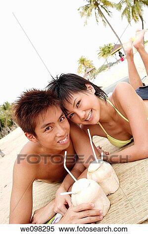 Stock Photography - Young asian couple relaxing at beach. Fotosearch