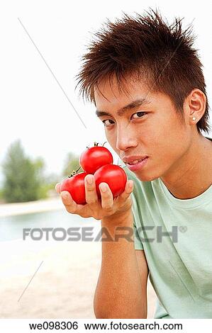 Young asian man with handful of tomatoes View Large Photo Image Stock Photograph - Young asian man with handful of tomatoes. Fotosearch