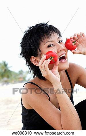 Young asian woman holding tomatoes View Large Photo Image Stock Image - Young asian woman holding tomatoes. Fotosearch