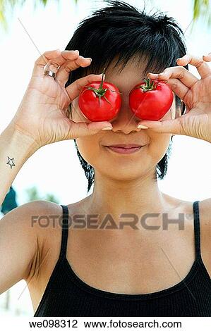Stock Image - young asian woman holding tomatoes. Fotosearch