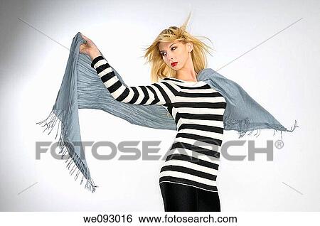 Young blond woman in striped top holding a scarf in the wind on gray background View Large Photo Image Stock Photograph - Young blond woman in striped top holding a scarf in the wind on gray background. Fotosearch
