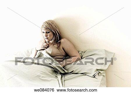 Young blond woman sitting on her bed View Large Photo Image Stock Photograph - Young blond woman sitting on her bed. Fotosearch
