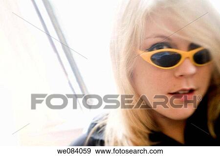 Young blond woman, wearing sunglasses, standing by her living room window View Large Photo Image Stock Photo - Young blond woman, wearing sunglasses, standing by her living room window. Fotosearch